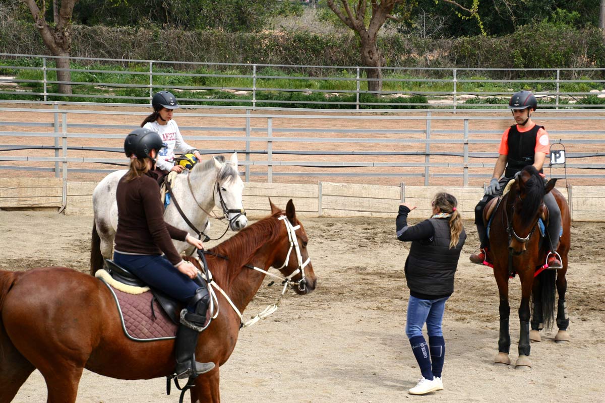 Alumnos montando a caballo junto a instructor