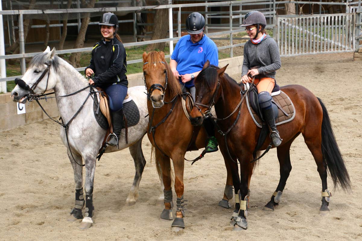 Grupo de alumnos de equitación montando a caballo